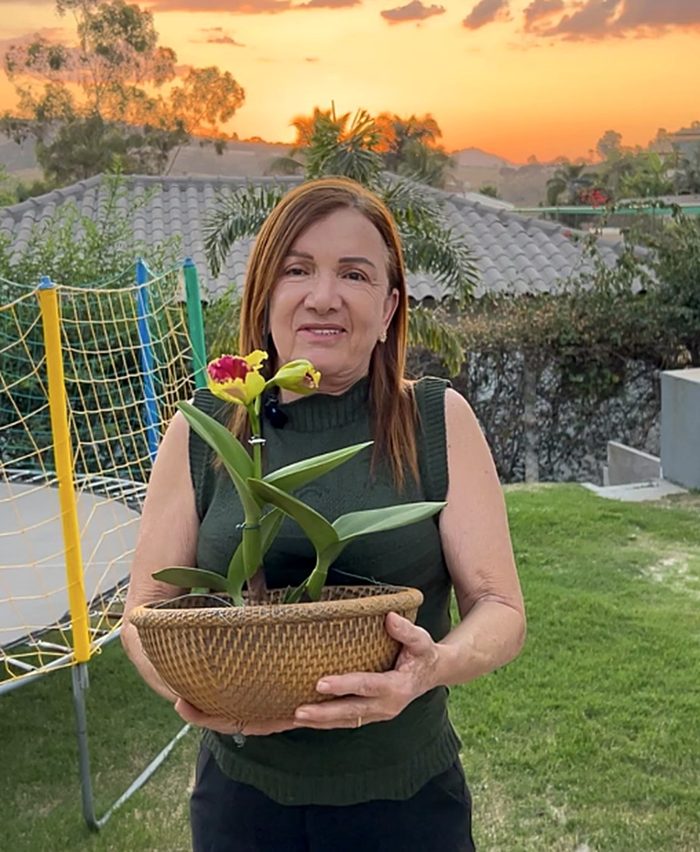 Rosângela sorrindo com uma Cattleya florida